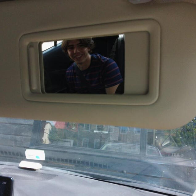 Piper, smiling in the mirror of a car.